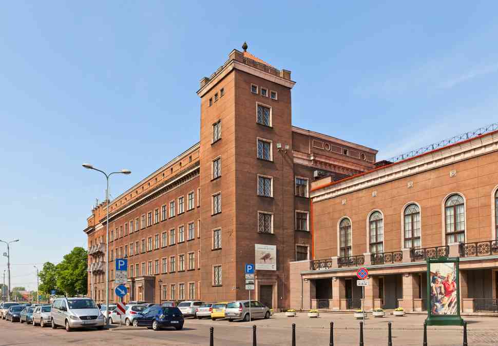A building with cars packed in front of it and cars moving