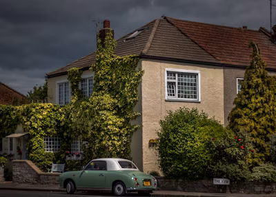 Green and white coupe parked outside a house